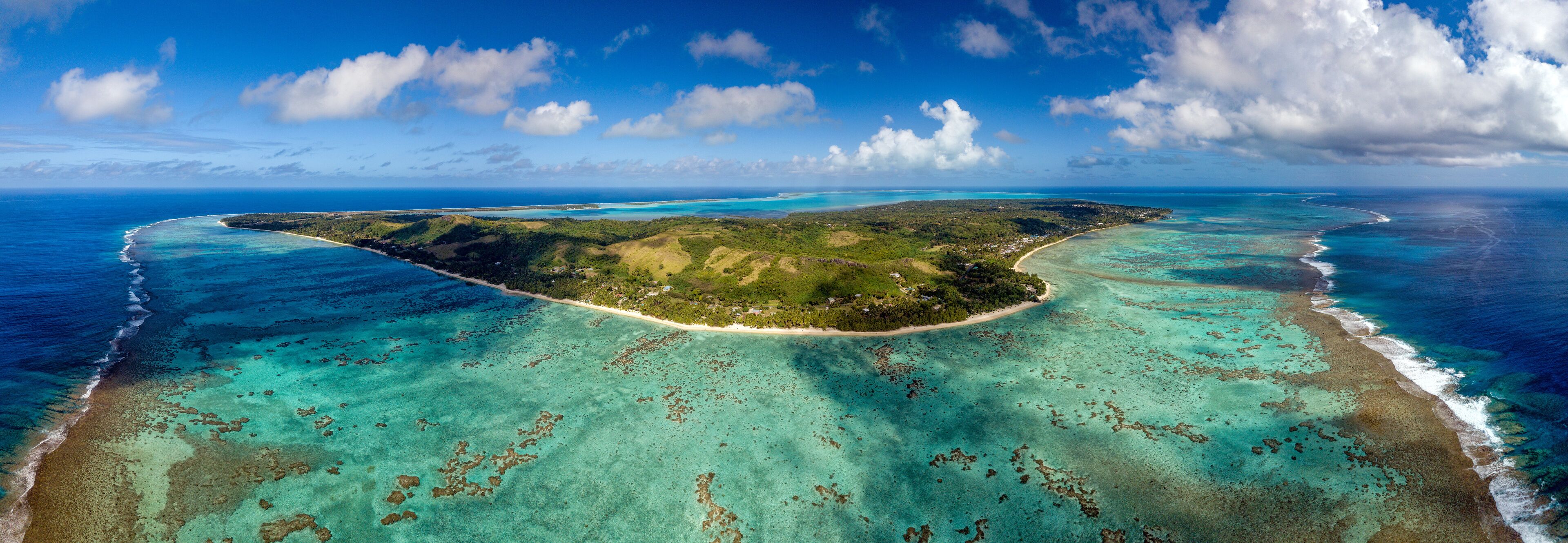 Vista aérea de una isla tropical con aguas turquesas cristalinas, playas de arena y exuberante vegetación.