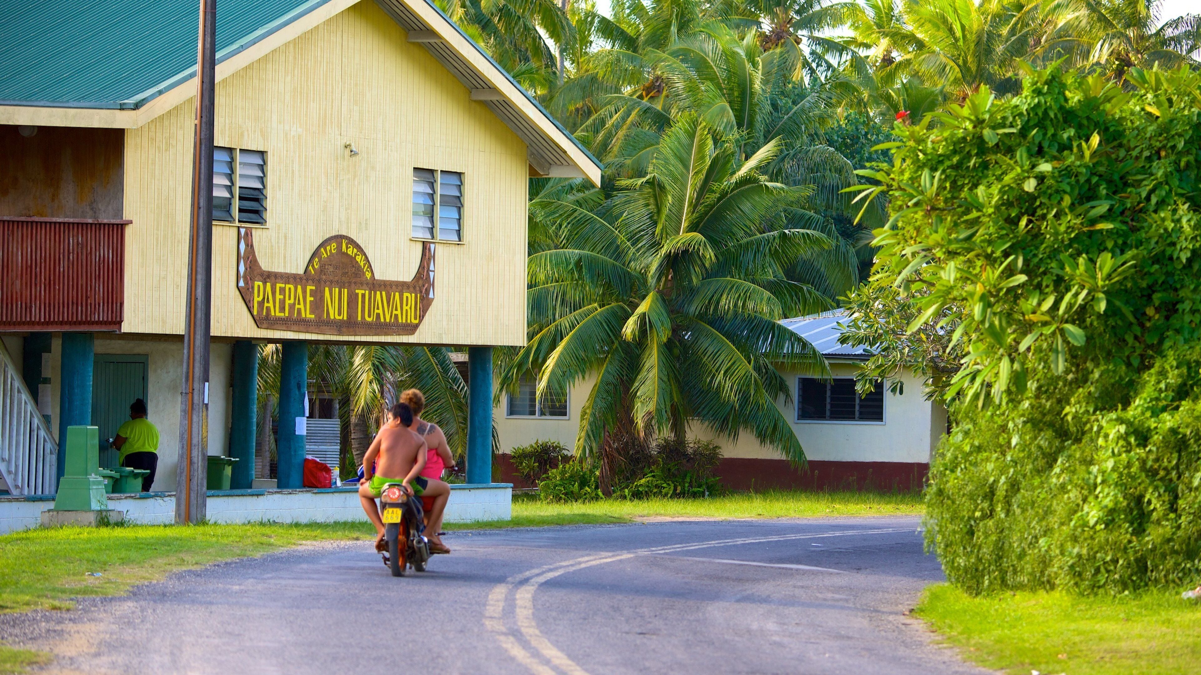 A building with a sign reading "Papei Nui Tuavaru" and a person riding a motorcycle.