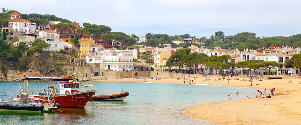 A coastal town with a sandy beach, boats, and colorful buildings.