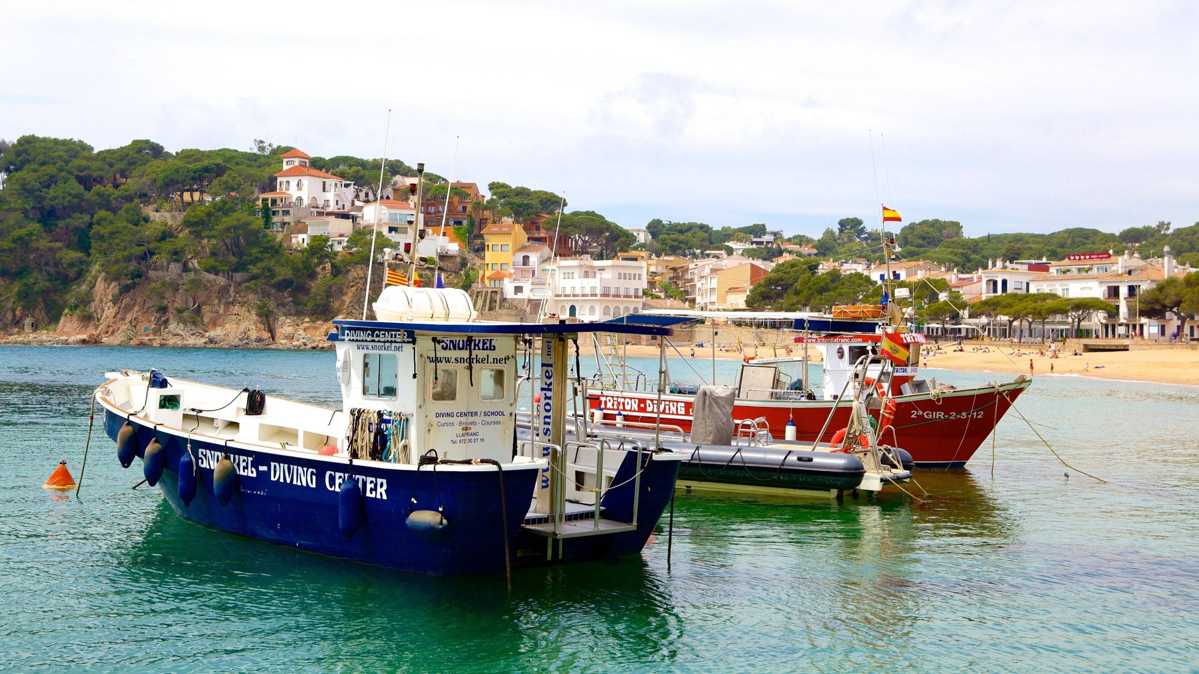 Un puerto con barcos, un centro de buceo y un pueblo costero con edificios.