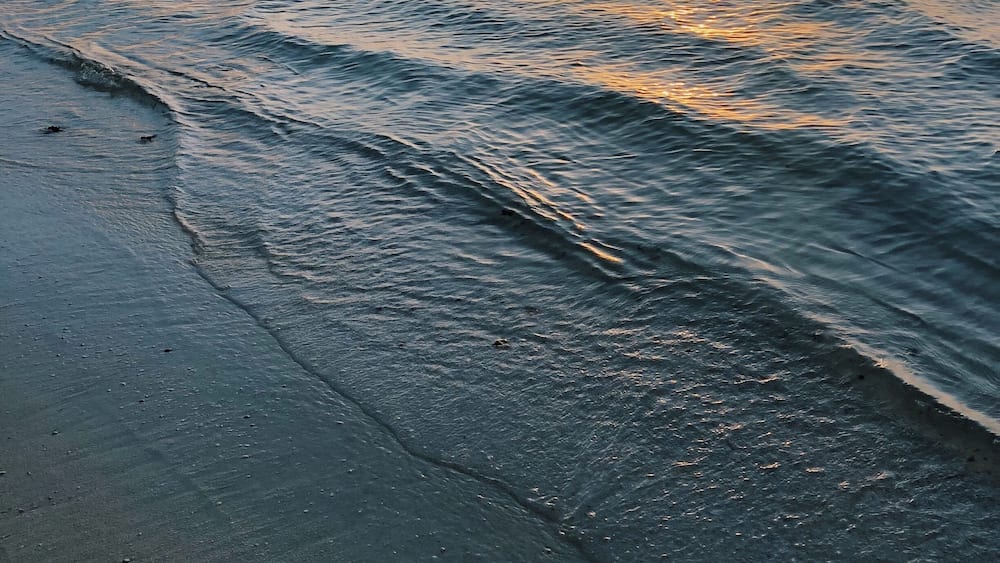 Une plage où les vagues viennent doucement lécher le rivage.