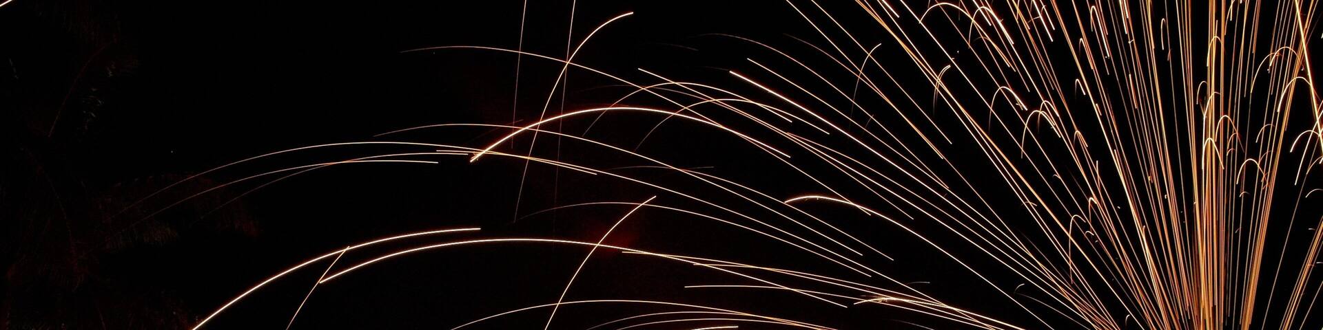 A person performing fire spinning with sparks flying around.