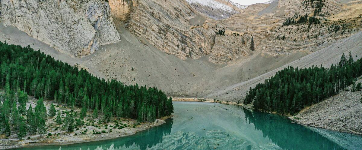 A mountain lake surrounded by forested slopes and rocky cliffs.