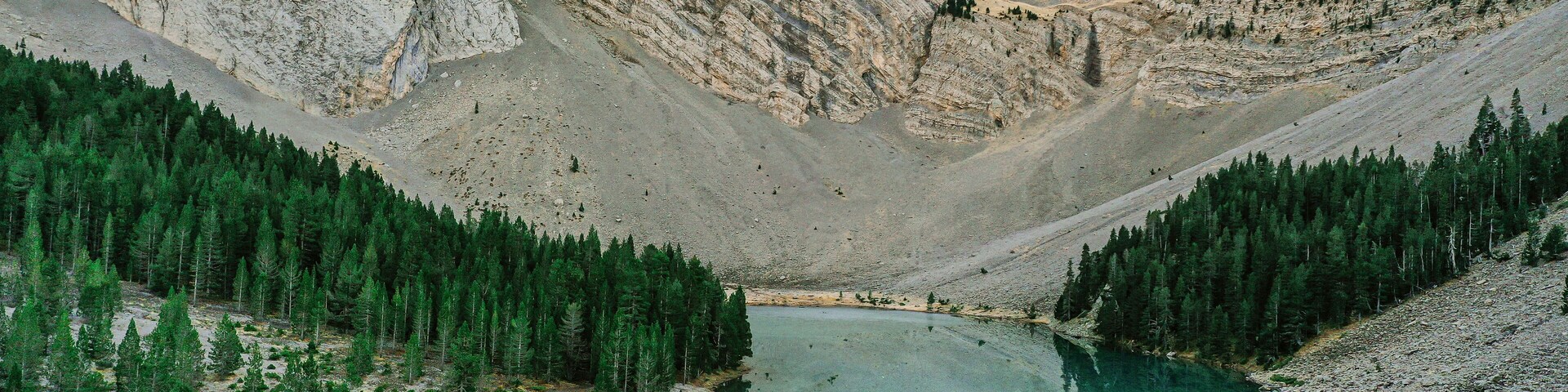A mountain lake surrounded by forested slopes and rocky cliffs.