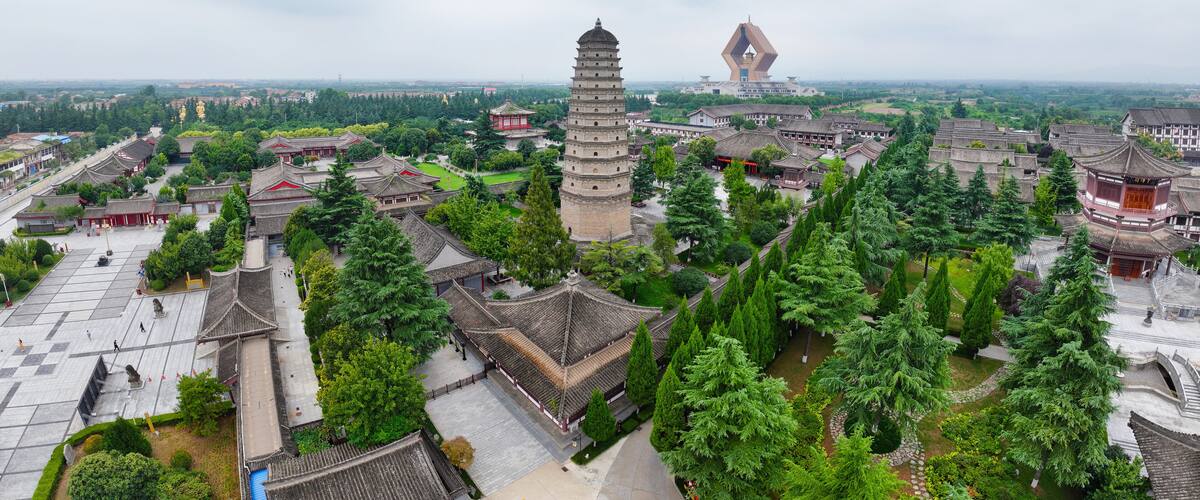 A traditional Chinese architectural complex with pagoda-style towers, surrounded by lush greenery and traditional buildings.