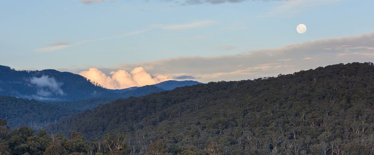 A mountain range with a full moon in the sky.