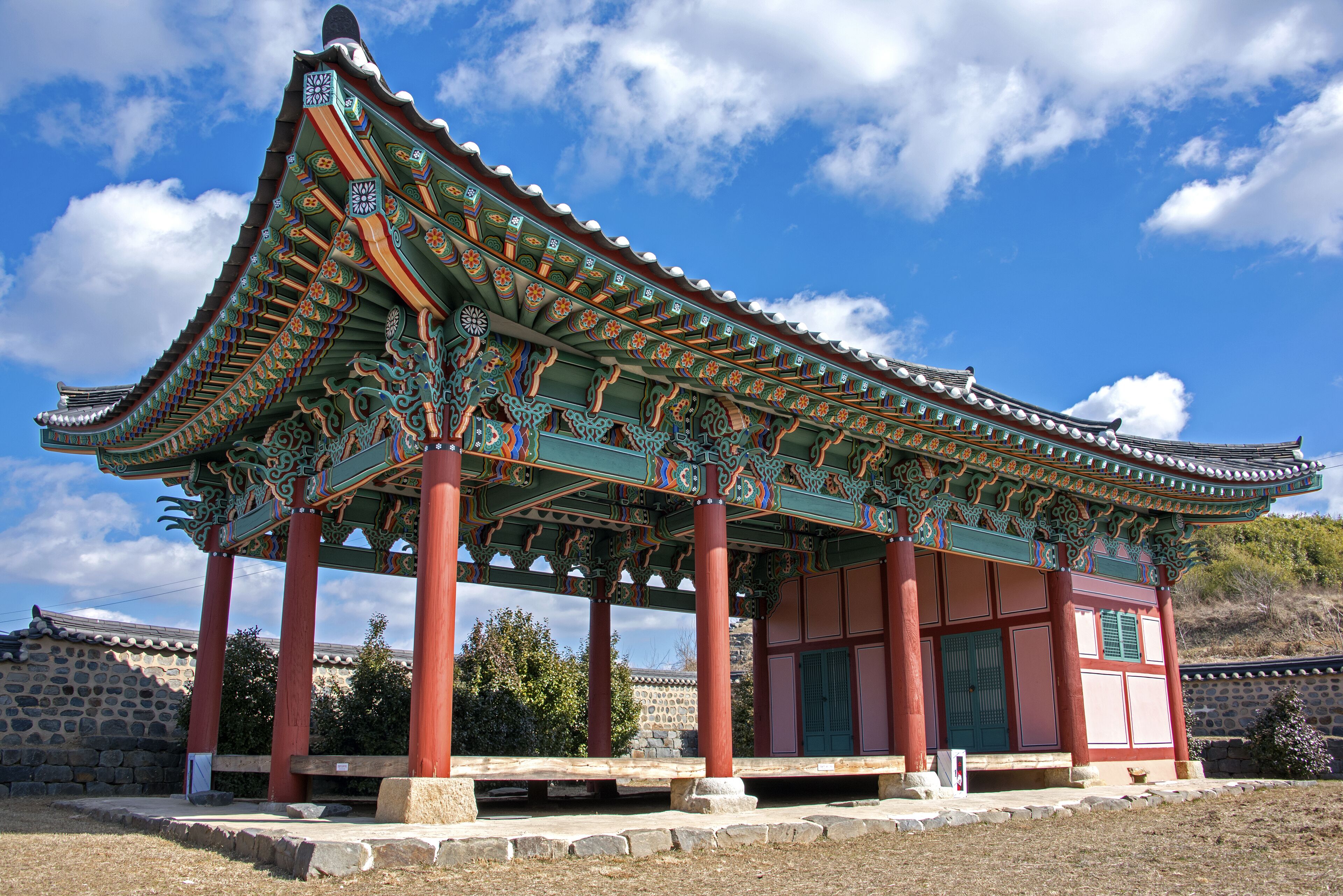 A traditional Korean pavilion with ornate roof and red pillars.