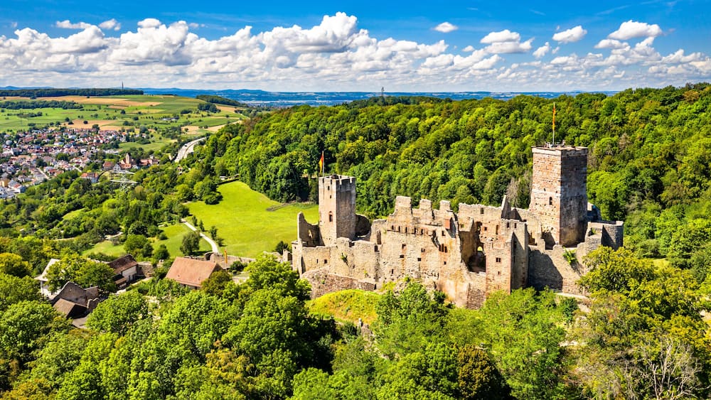 A medieval castle surrounded by lush greenery and a small village.