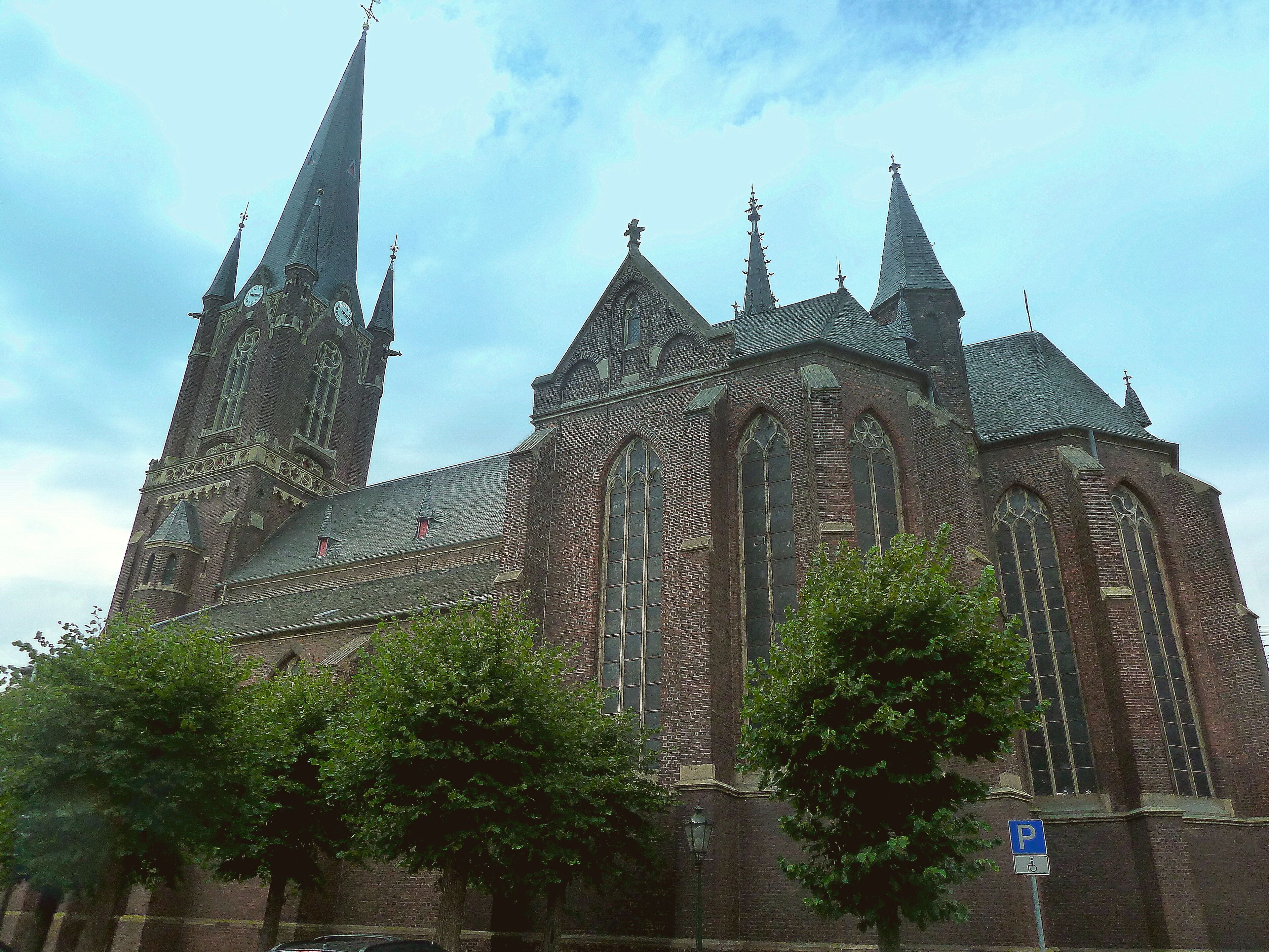 A large brick church with multiple spires and a clock tower.