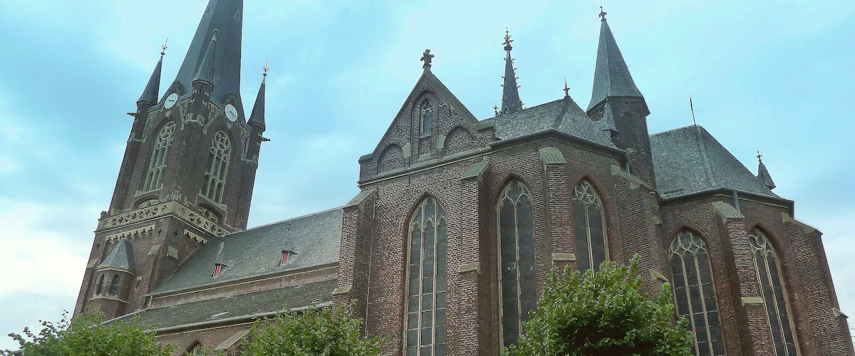 A large brick church with multiple spires and a clock tower.