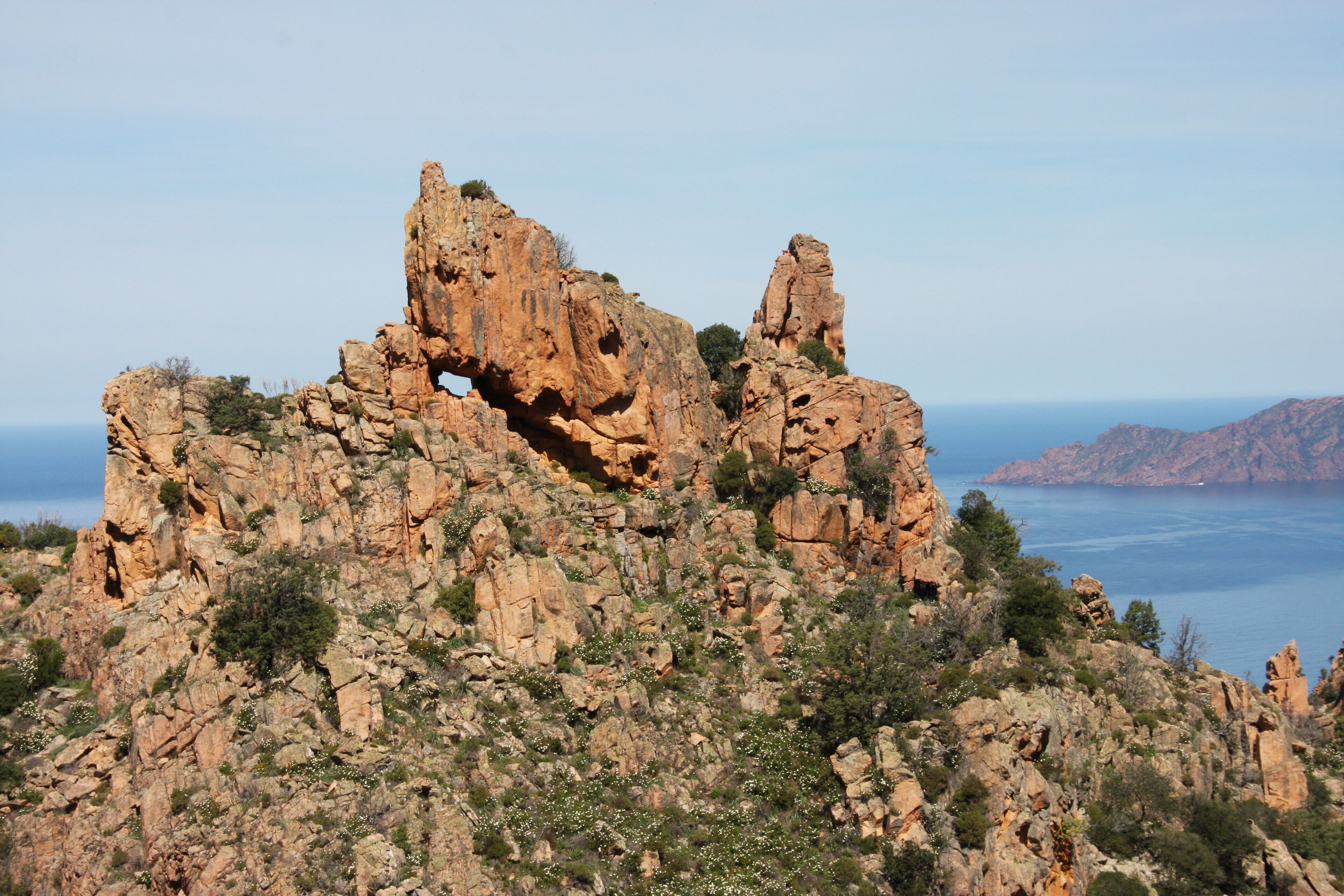 A rocky landscape with a prominent rock formation featuring a natural arch.