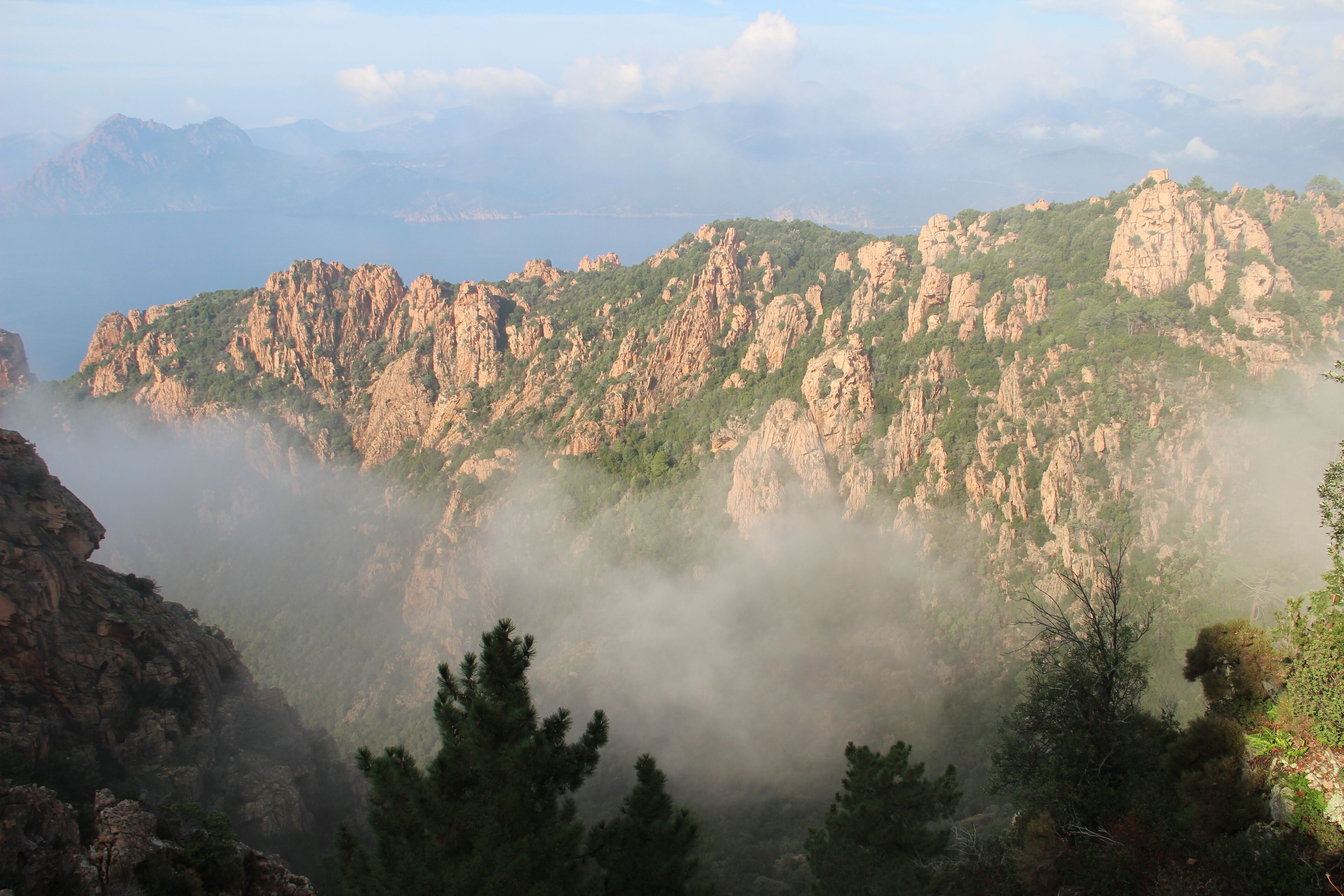 A mountainous landscape with rocky cliffs and dense greenery.