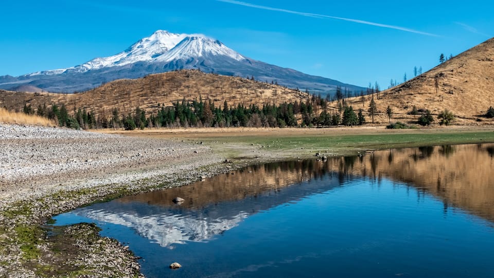 Snow capped mount shasta with a blue sky and reflection in lake
