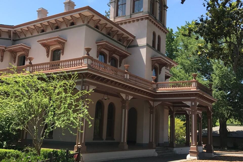 A large, historic building with a tower, arched windows, and a covered porch.