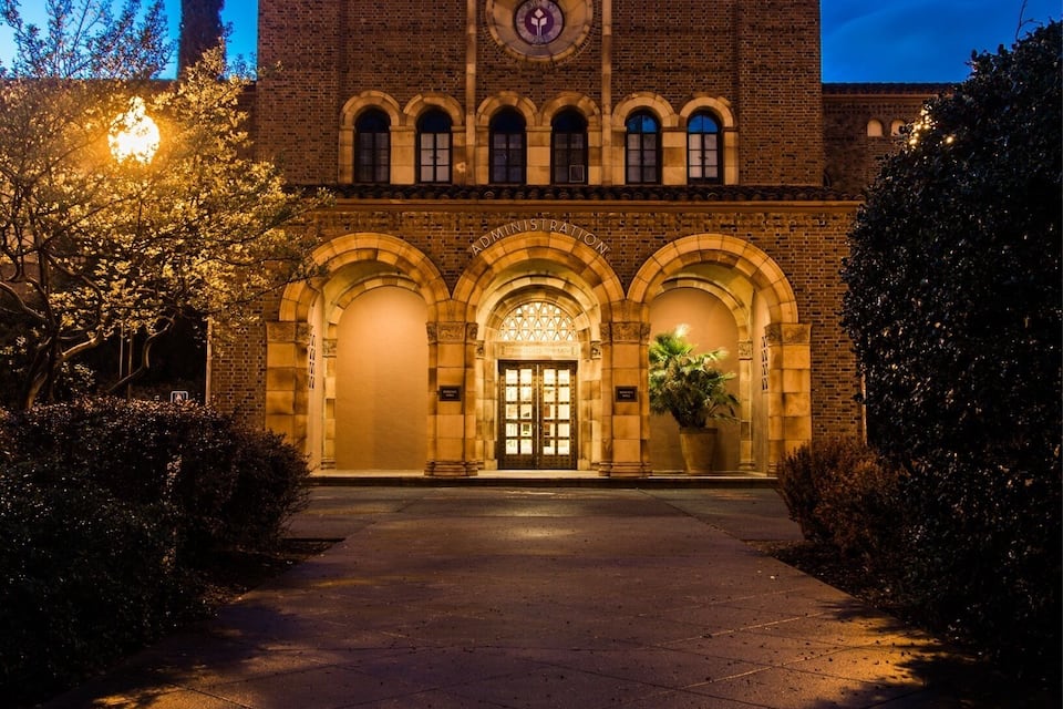 A historic building with arched entrances and a clock tower at dusk.