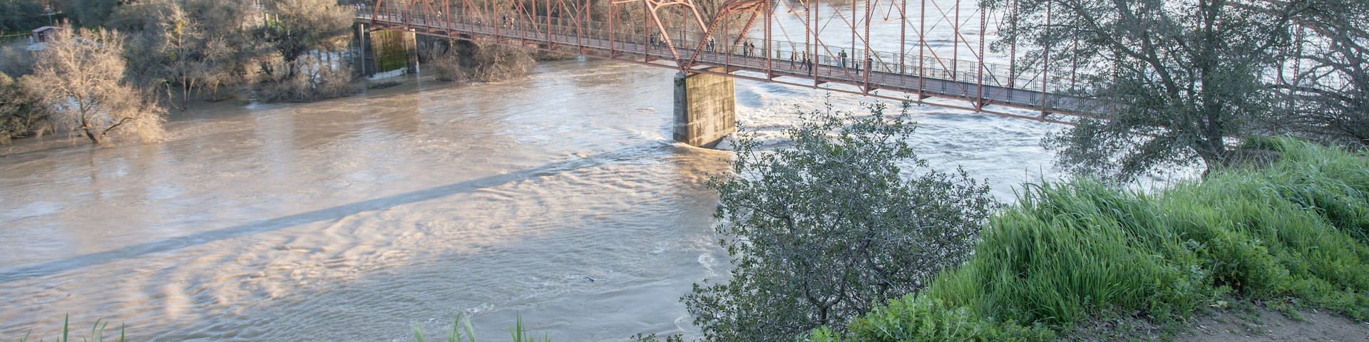 View of the red bridge, Fair Oaks, from the bluffs, with American River in flood