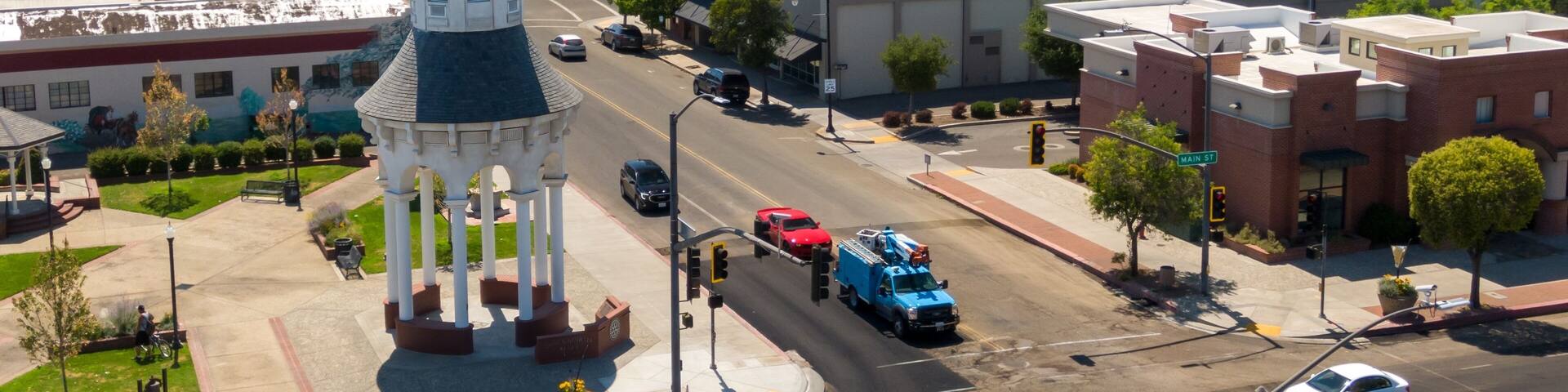 Aerial view of Red Bluff town square, showing a clock tower, businesses, and traffic. Cars and a utility truck are visible on the street. The Cone & Kimball Tower, Red Bluff, California, USA