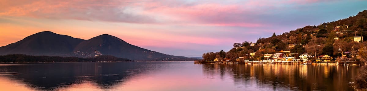 Un lac paisible, avec des montagnes en arrière-plan et un village sur la droite.
