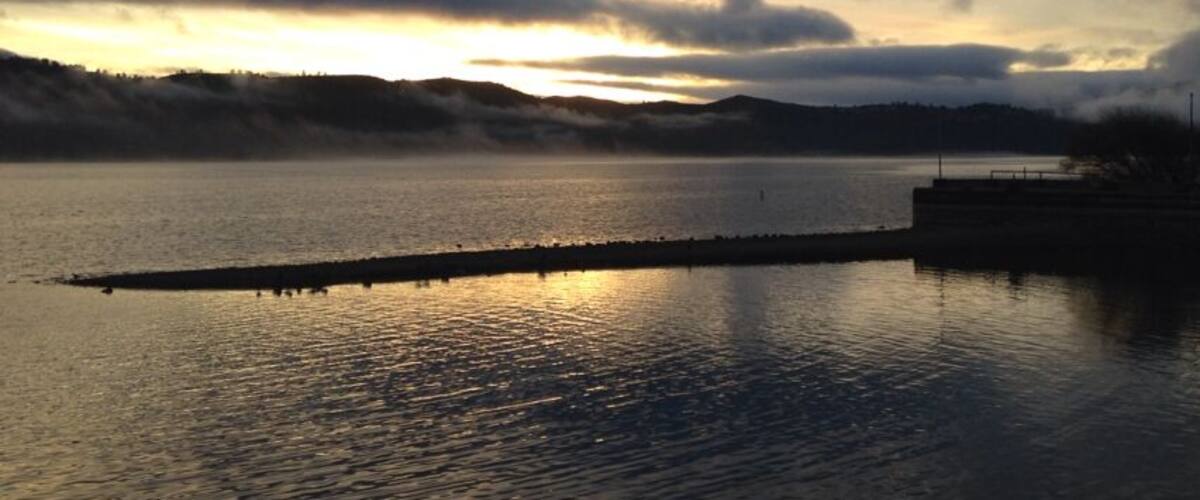 A calm lake at sunset with a dock extending into the water.