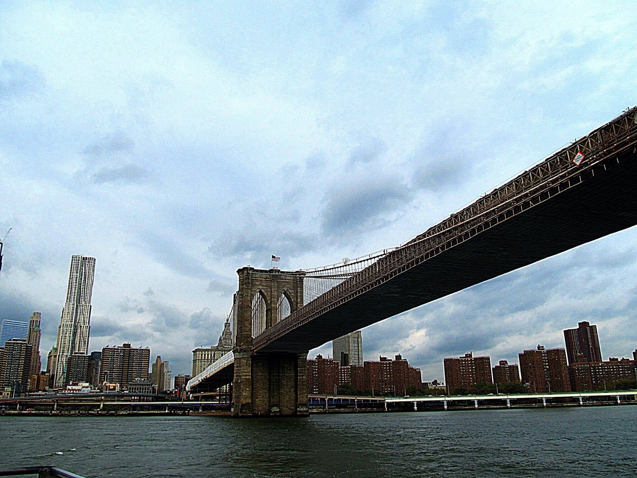 A bridge spanning a river with a city skyline in the background.