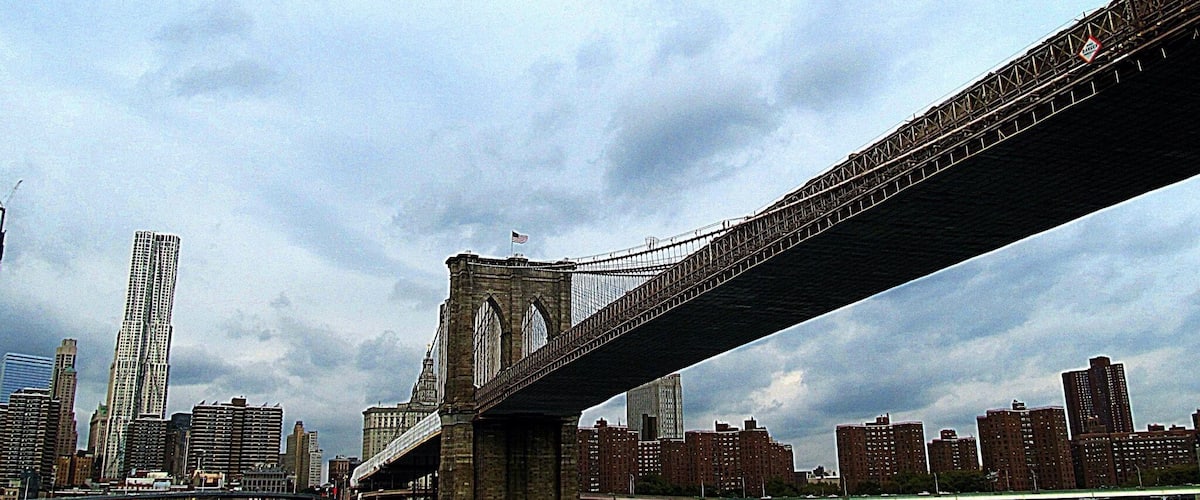 A bridge spanning a river with a city skyline in the background.