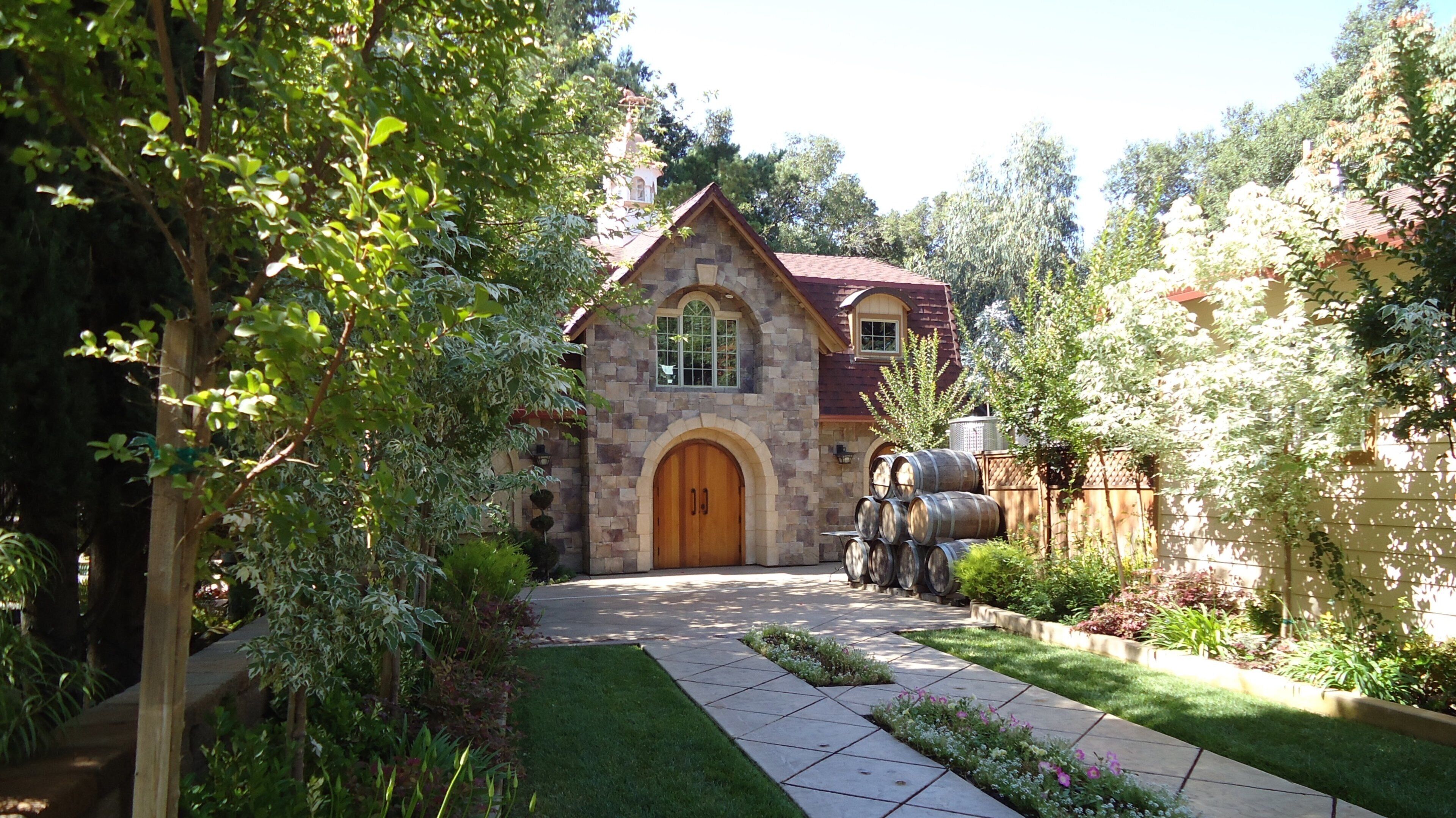 A stone house with a wooden door, surrounded by a garden with a stone pathway.