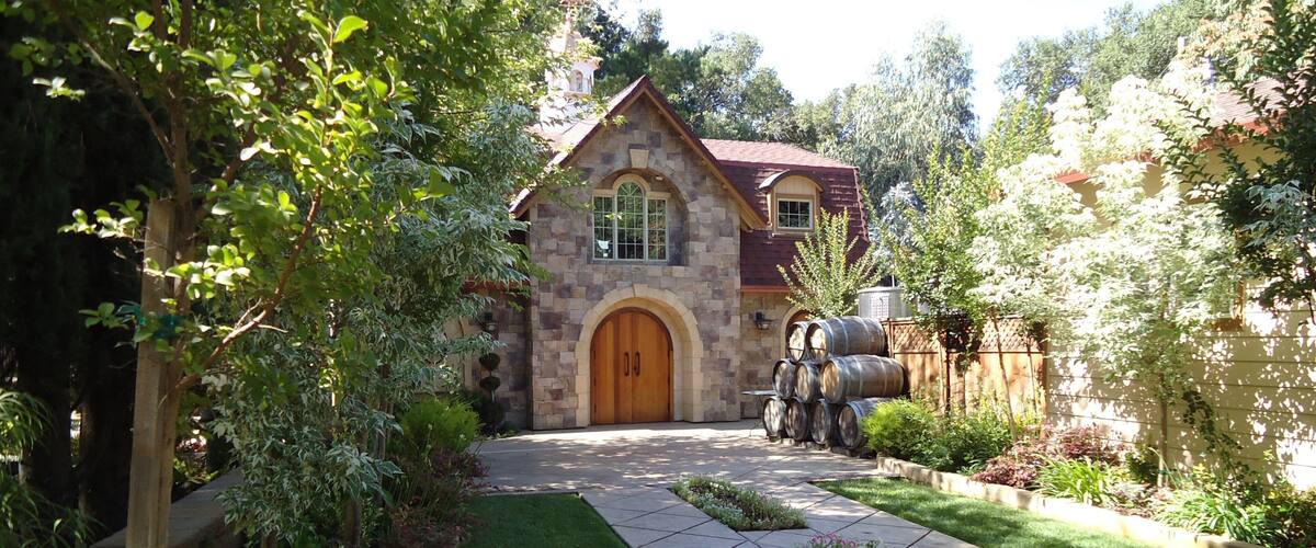 A stone house with a wooden door, surrounded by a garden with a stone pathway.