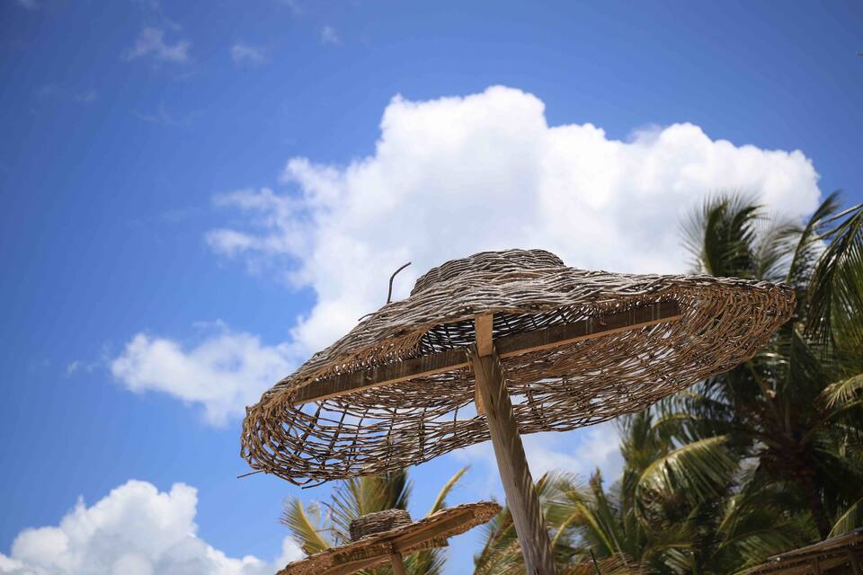 Un parasole intrecciato su uno cielo azzurro con nuvole.
