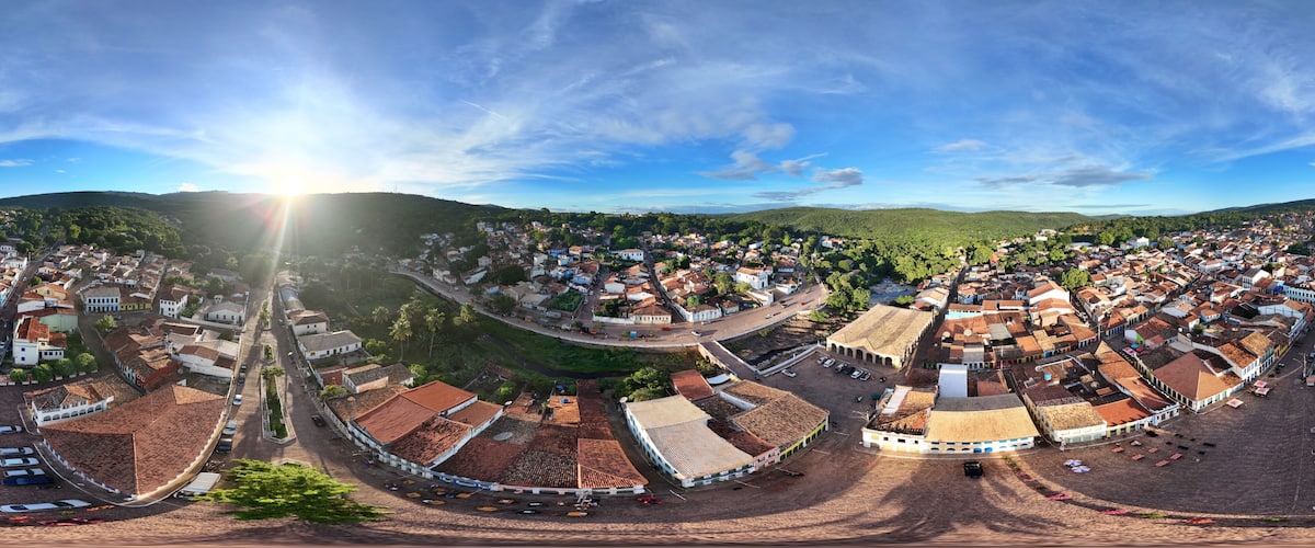 Vista panorámica de un pueblo histórico con edificios de tejados de terracota, una plaza central y colinas circundantes.