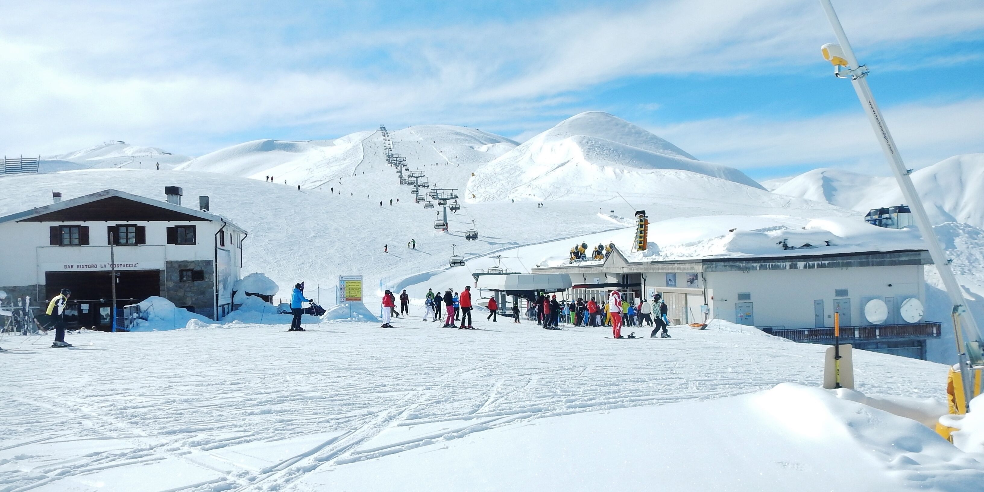 A snowy ski slope with a ski lift, a bar, and a mountain in the background.