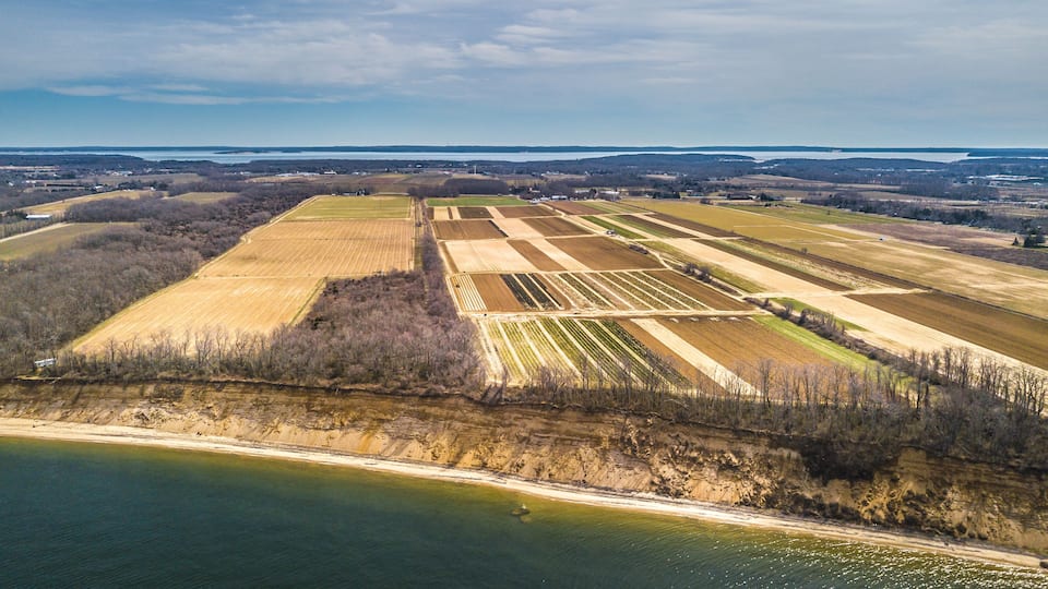 An aerial view of agricultural fields, a river, and a distant body of water.
