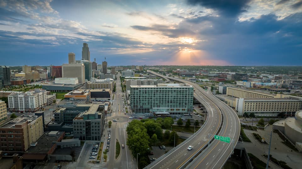 A cityscape with a prominent skyscraper, a highway, and a sunset.