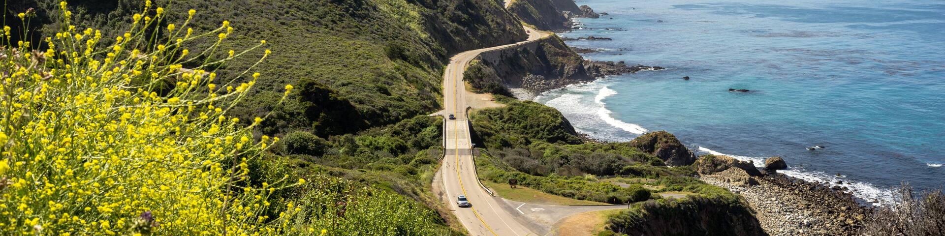 A coastal road winding through a mountainous landscape with a view of the ocean.