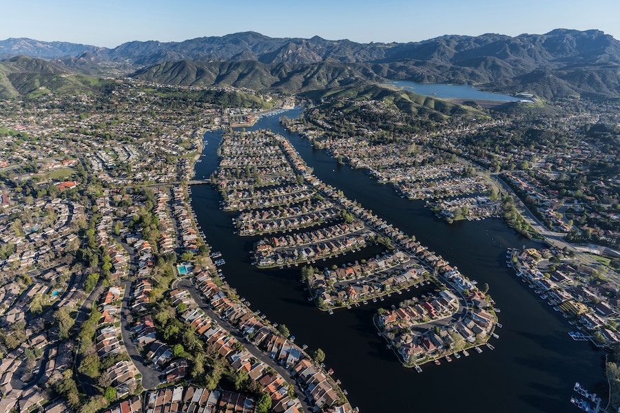 An aerial view of a river town with residential areas and docks along the water.