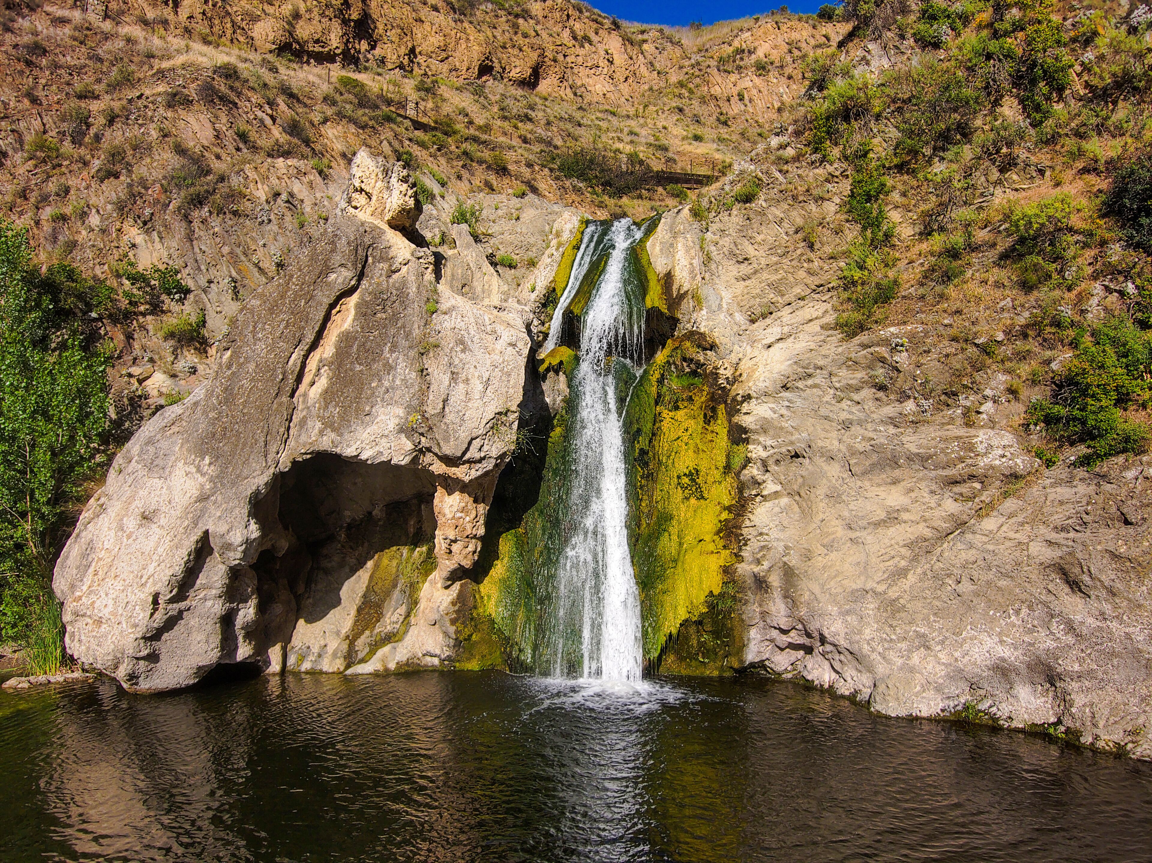 a stunning aerial shot of the waterfall covered in green and yellow algae and the surrounded mountain landscape at Paradise Falls in Thousand Oaks California USA