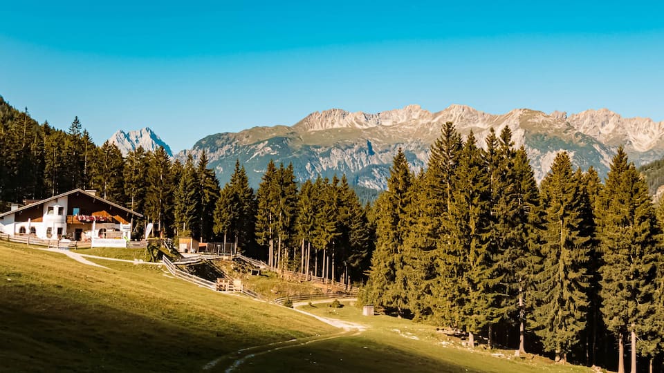 A house on a hillside with a mountain range in the background.