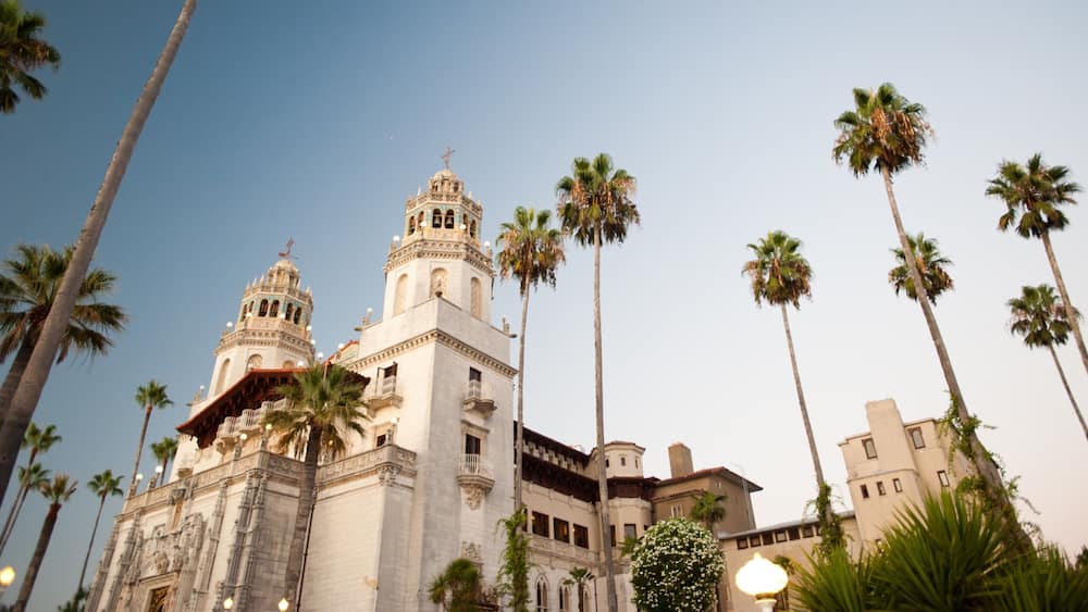 A historic building with ornate architecture, including a bell tower and a dome, surrounded by tall palm trees.