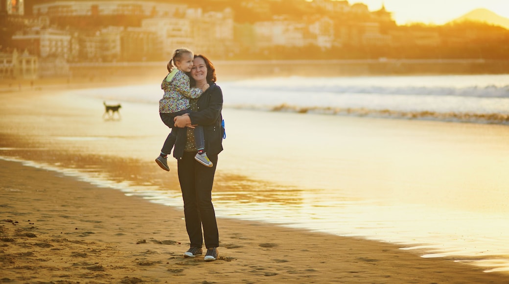 Woman holding little girl on La Concha beach in San Sebastian (Donostia), Basque Country, Spain