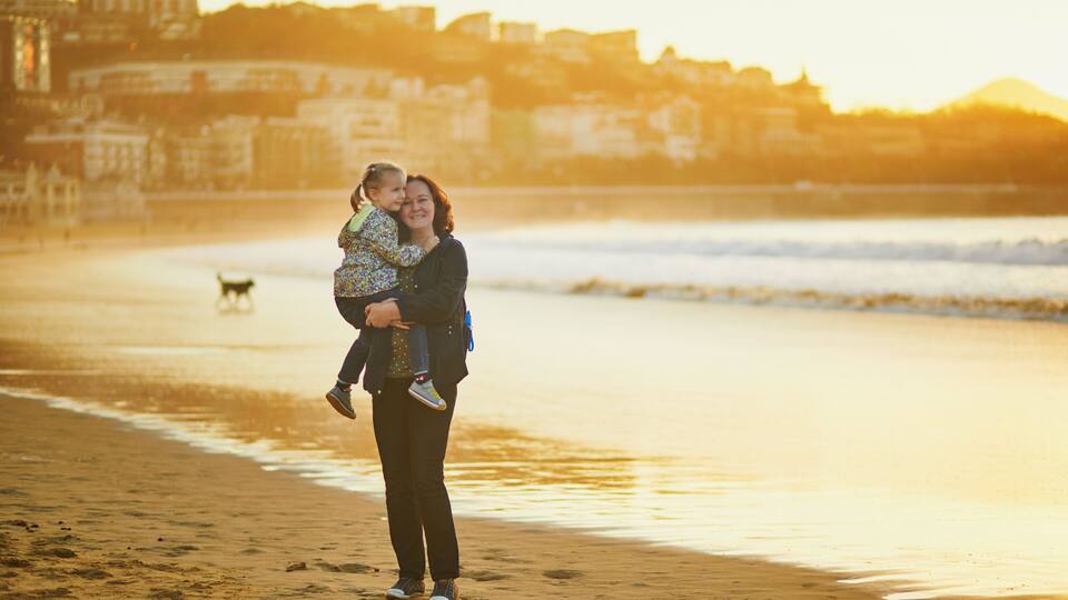 Woman holding little girl on La Concha beach in San Sebastian (Donostia), Basque Country, Spain