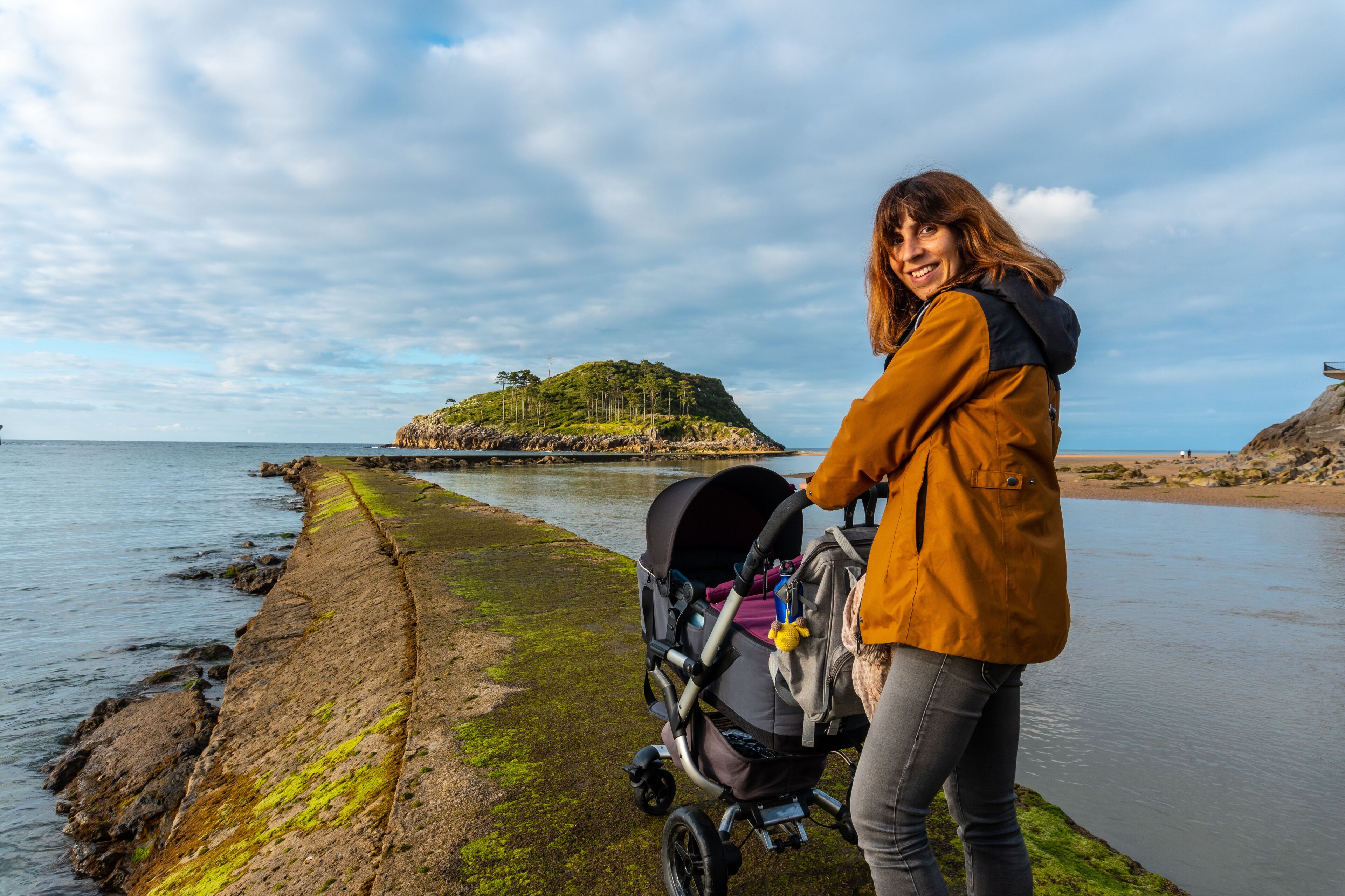 A mother with her son on the footbridge to go to San Nicolas Island at low tide from Isuntza beach in Lekeitio, Basque Country. Bay of Biscay. Spain