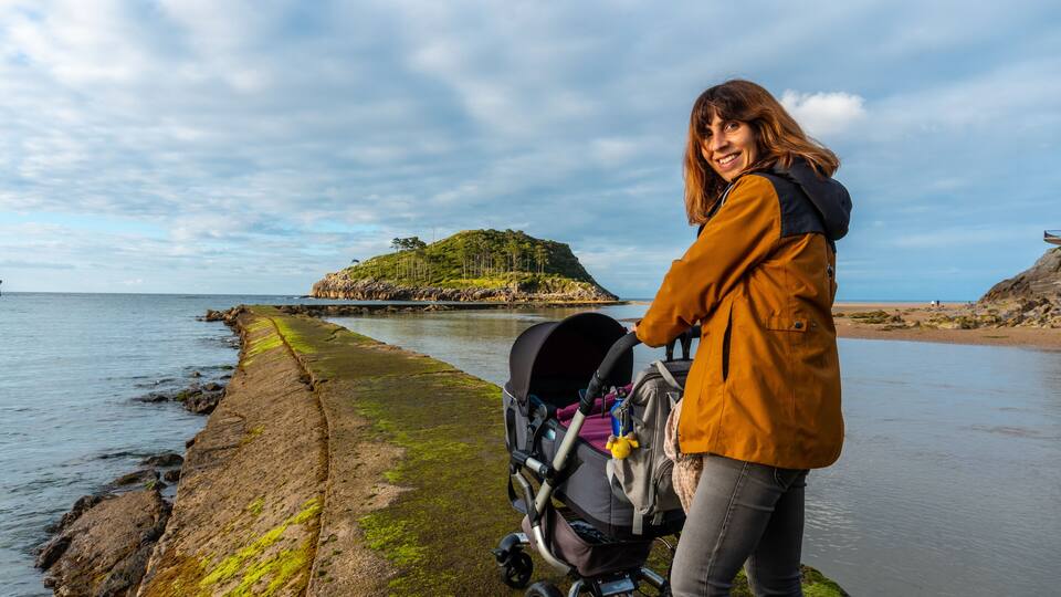 A mother with her son on the footbridge to go to San Nicolas Island at low tide from Isuntza beach in Lekeitio, Basque Country. Bay of Biscay. Spain