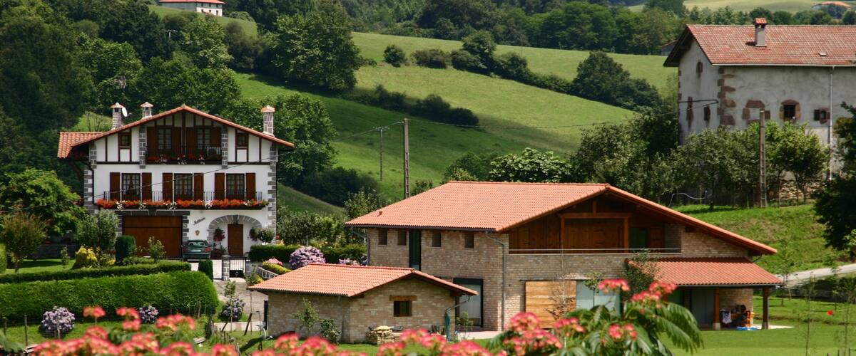 A rural landscape with a large house, smaller buildings, and lush green fields.