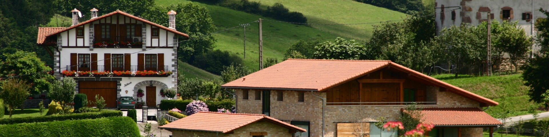 A rural landscape with a large house, smaller buildings, and lush green fields.