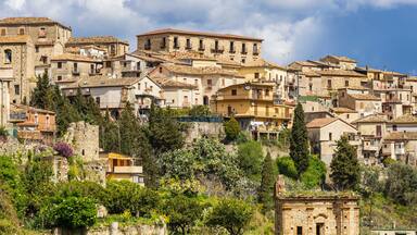 A hillside village with historic stone buildings and lush greenery.