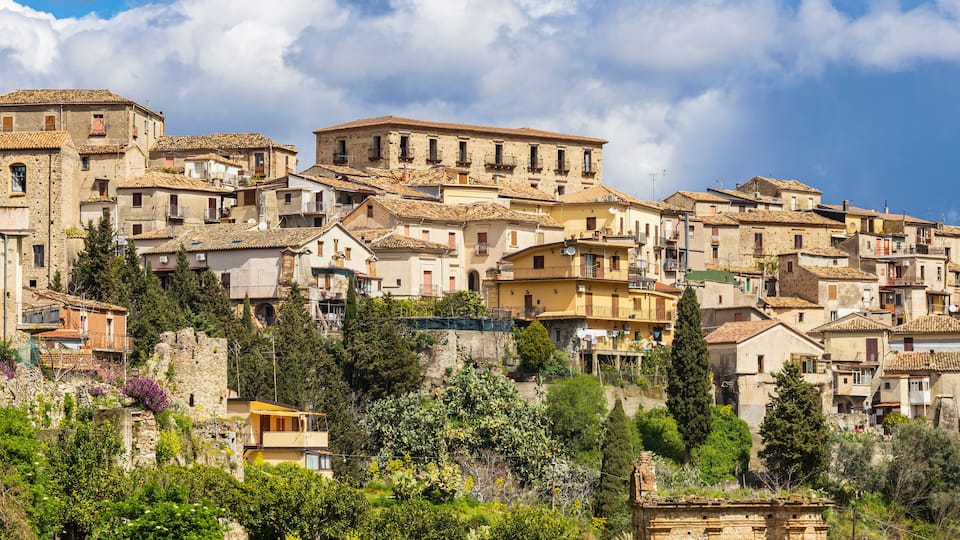 A hillside village with historic stone buildings and lush greenery.