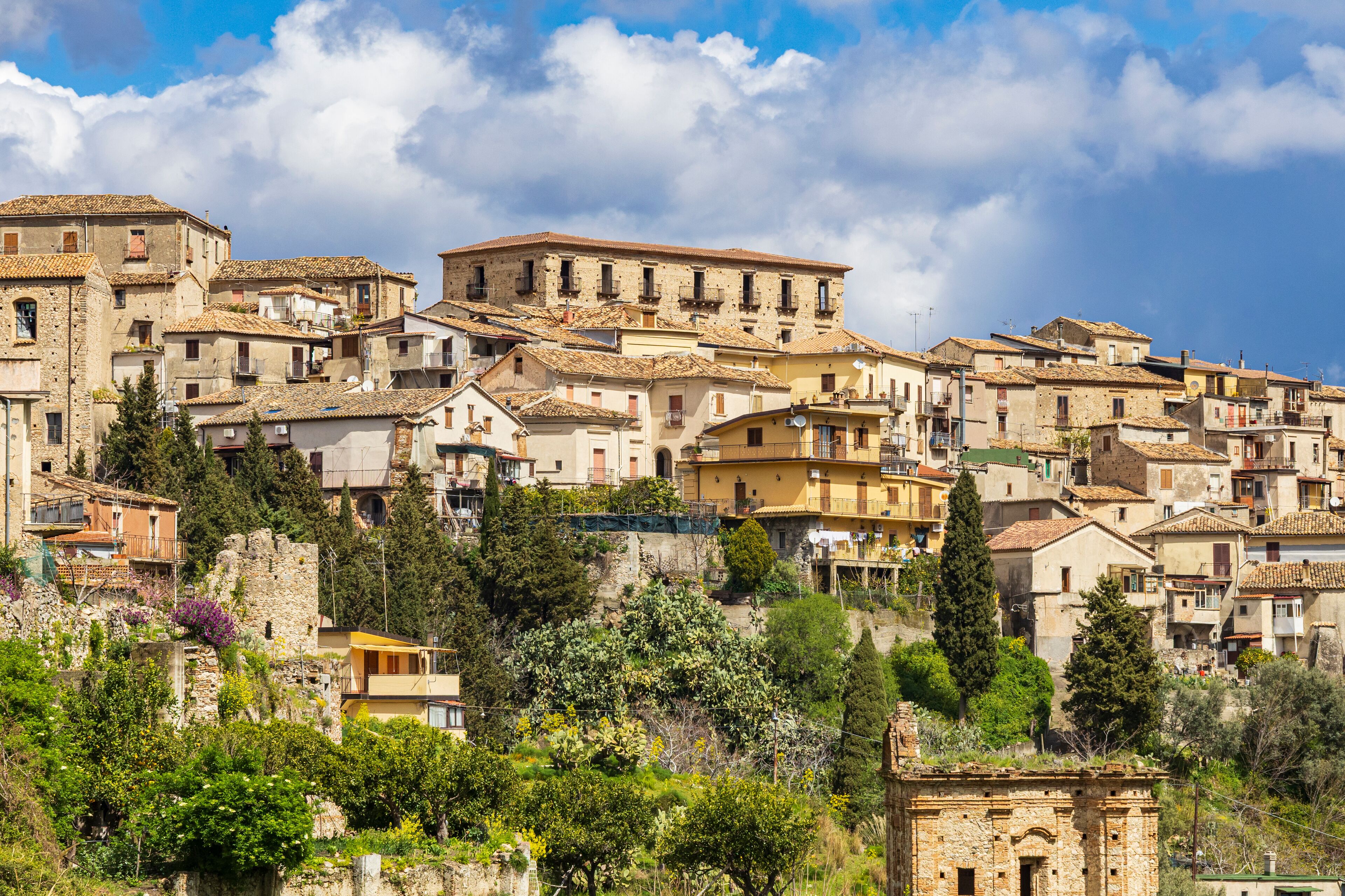 A hillside village with historic stone buildings and lush greenery.