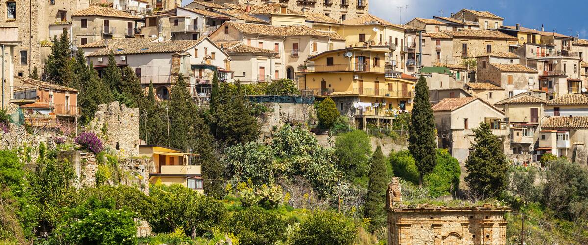 A hillside village with historic stone buildings and lush greenery.