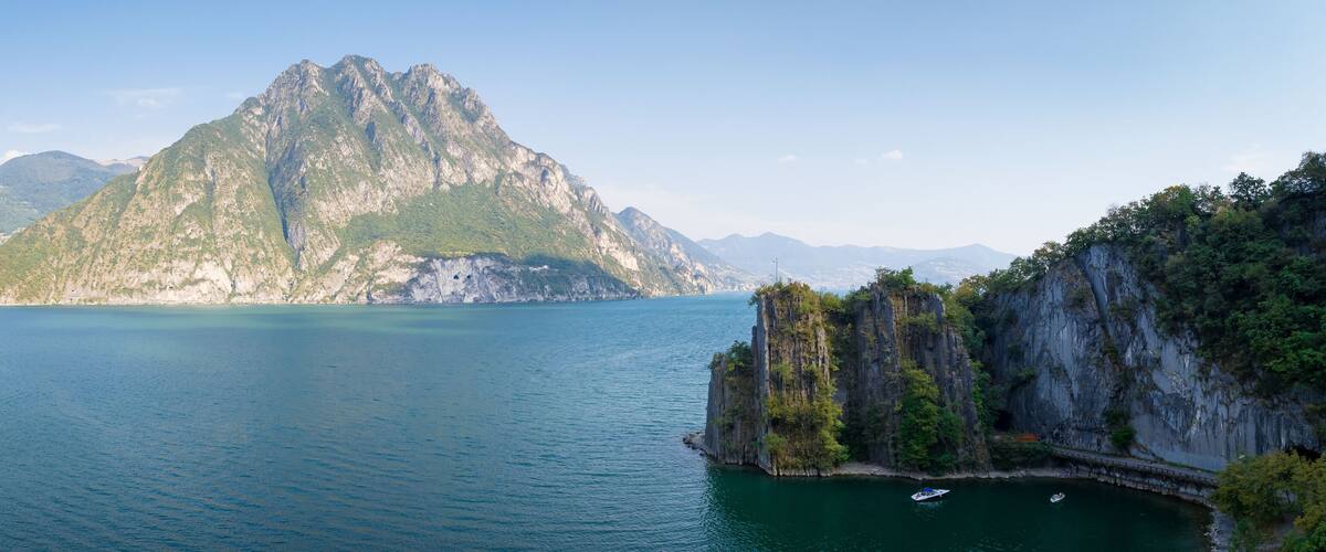 A mountain surrounded by calm water, with a bridge connecting two cliffs.