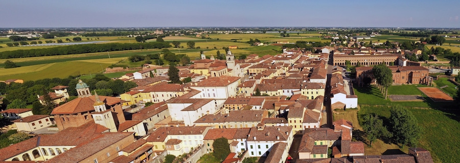 Un pueblo histórico con edificios de tejados de terracota, una iglesia destacada y campos verdes circundantes.