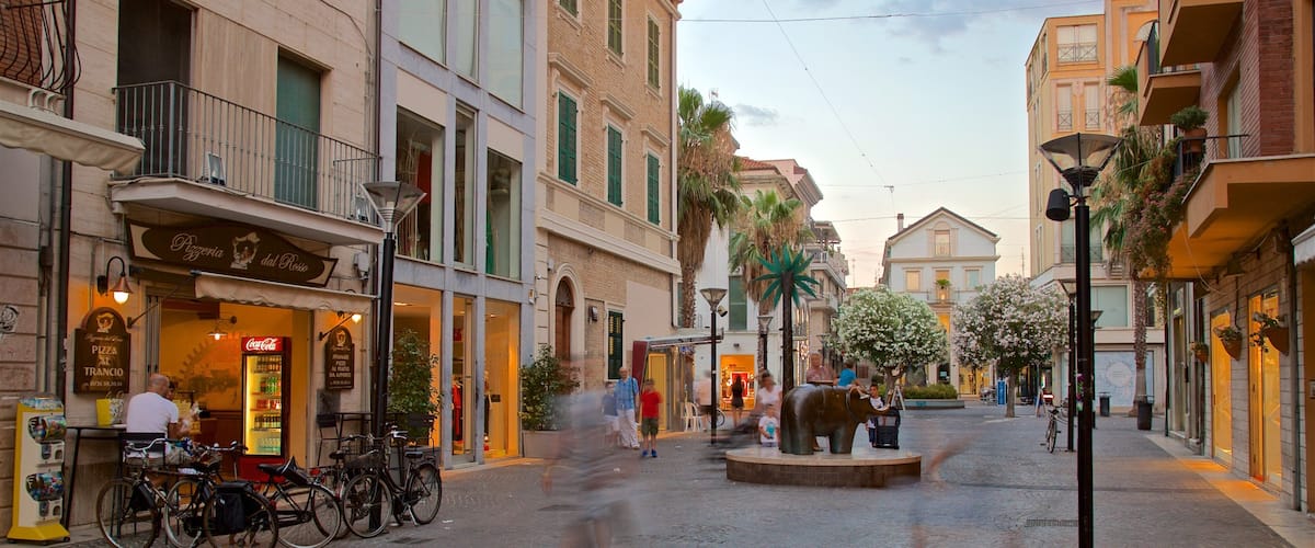 A cobblestone street lined with historic buildings, a fountain, and bicycles parked along the sidewalk.